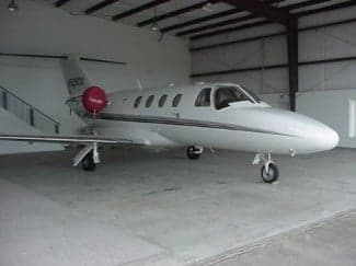 A Cessna CitationJet is parked inside a hangar.