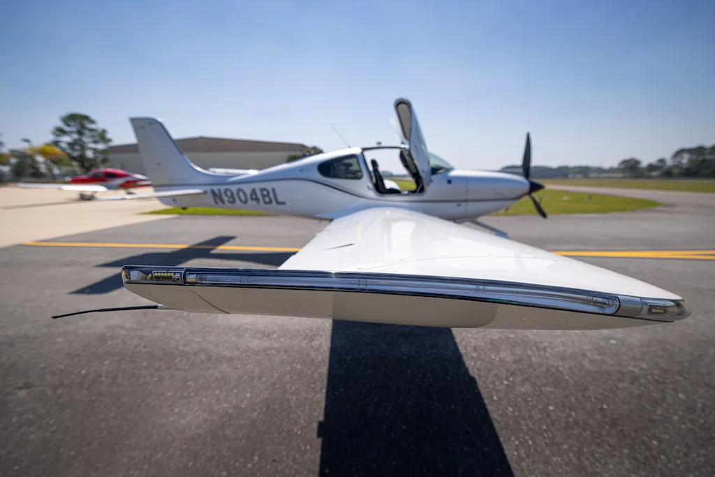 A close-up view of the wing and fuselage of a silver Cirrus SR22 aircraft, showing the N904BL registration.
