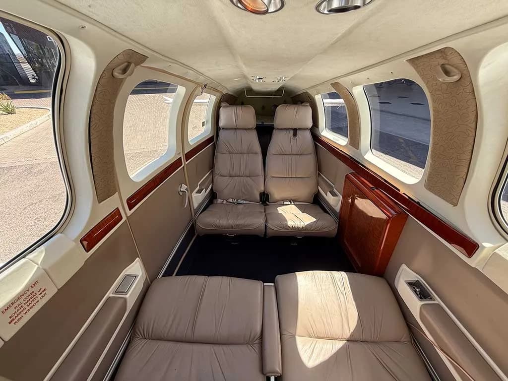 The interior cabin of the aircraft, showing four tan leather seats in a club configuration.