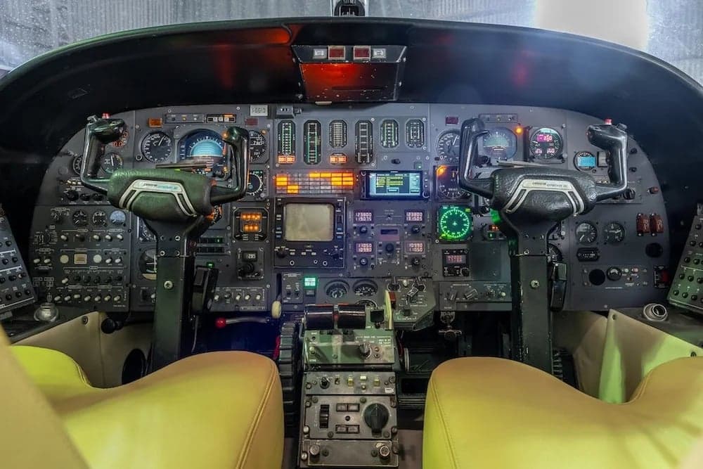 The cockpit of a Cessna Citation II features a full instrument panel and tan leather seats.