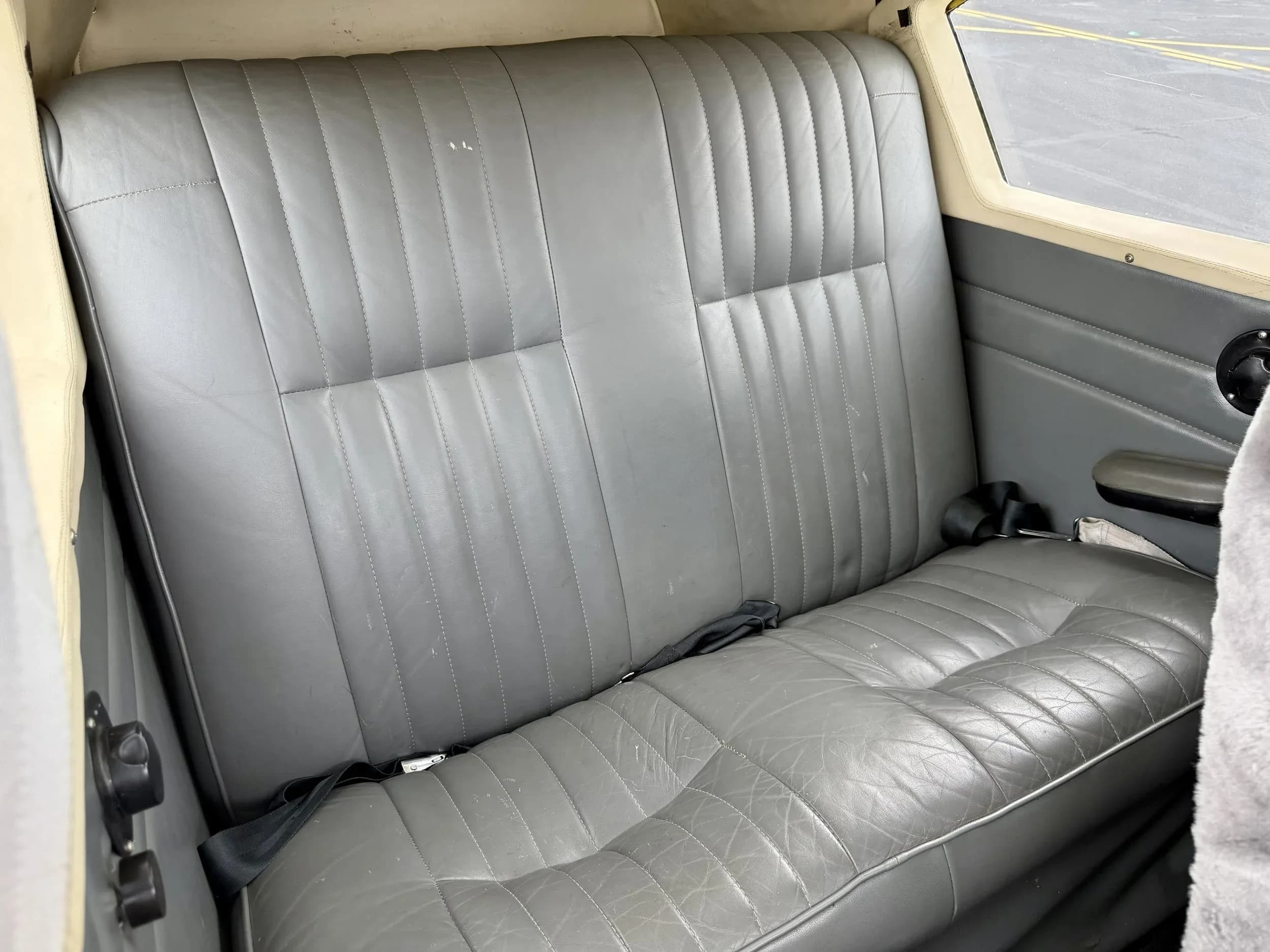 The rear grey leather bench seat of a Piper Comanche N7727P.