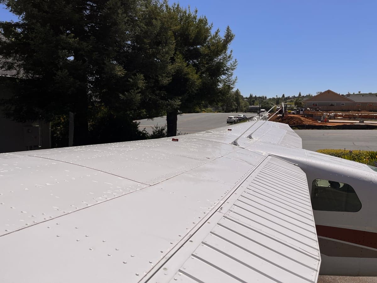 A high angle view of the wing of a Cessna Skymaster N732JM on the ground.