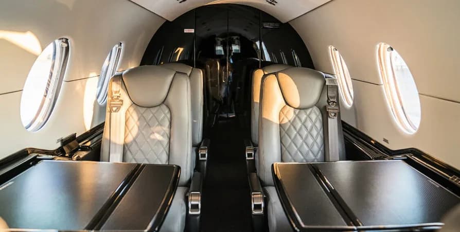 Interior view of the aircraft cabin showing leather seats and tables.
