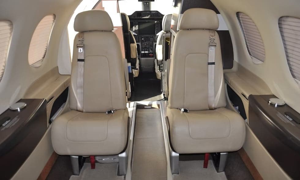 Interior view of the aircraft showing two seats with tables.
