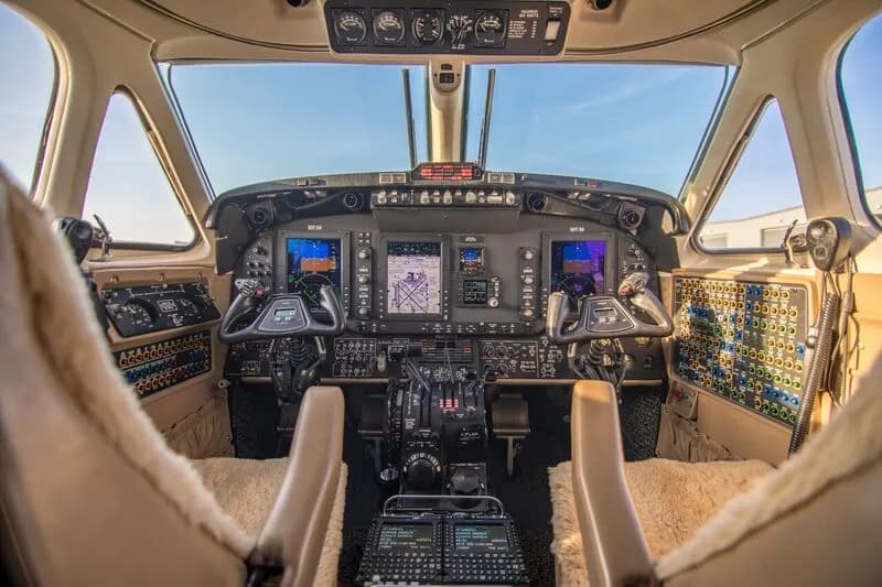 The cockpit of a turboprop aircraft features a modern glass panel display and dual yokes.