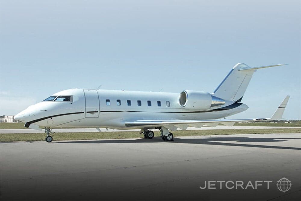 Side view of a white Bombardier Challenger aircraft on the tarmac.
