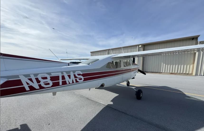 A close-up side view of the fuselage of Cessna 182 Skylane (N87MS) showing the tail number and red stripe.