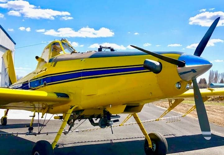 Close-up of the yellow and blue Air Tractor AT-400 aircraft's nose and propeller.