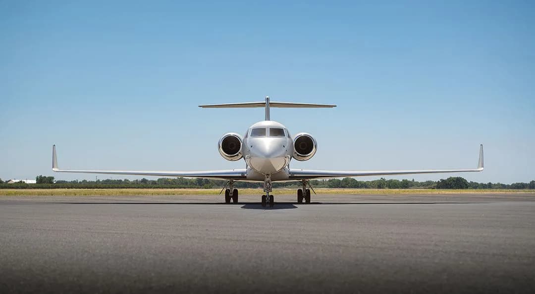 A head-on view of a white Gulfstream G550 business jet parked on an airfield.