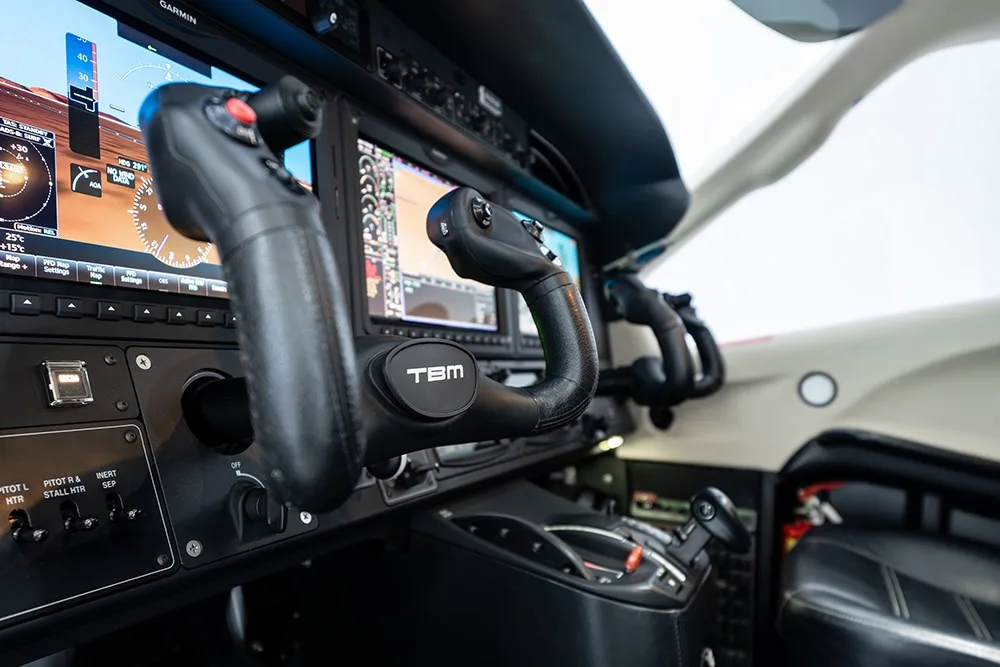 A detailed view of the TBM 930 cockpit yokes and central control panel with multiple screens.