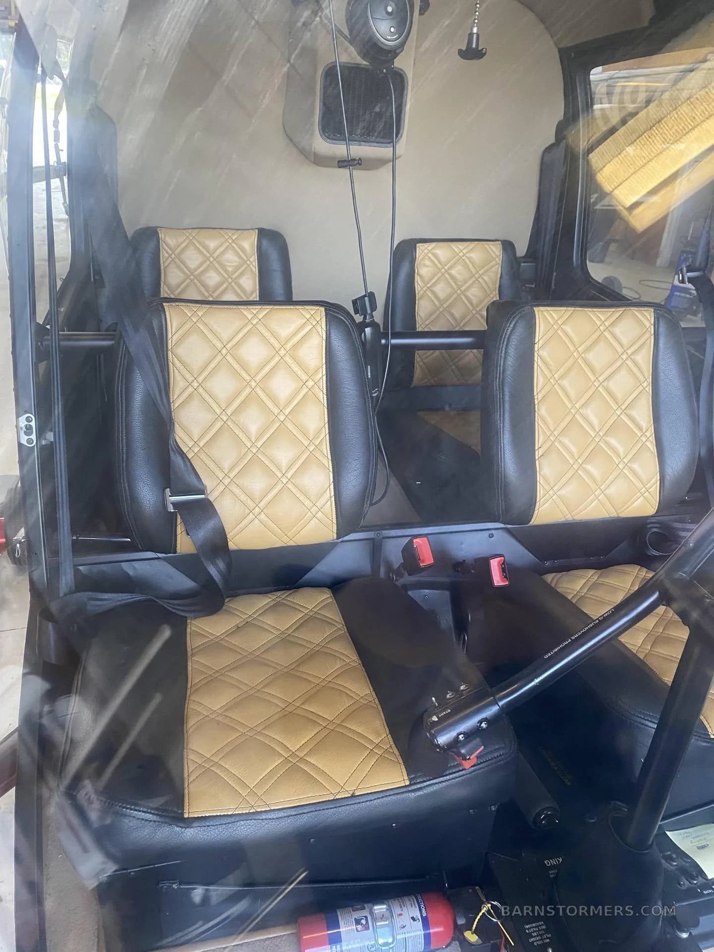The interior cabin of a helicopter with four black and tan quilted leather seats.