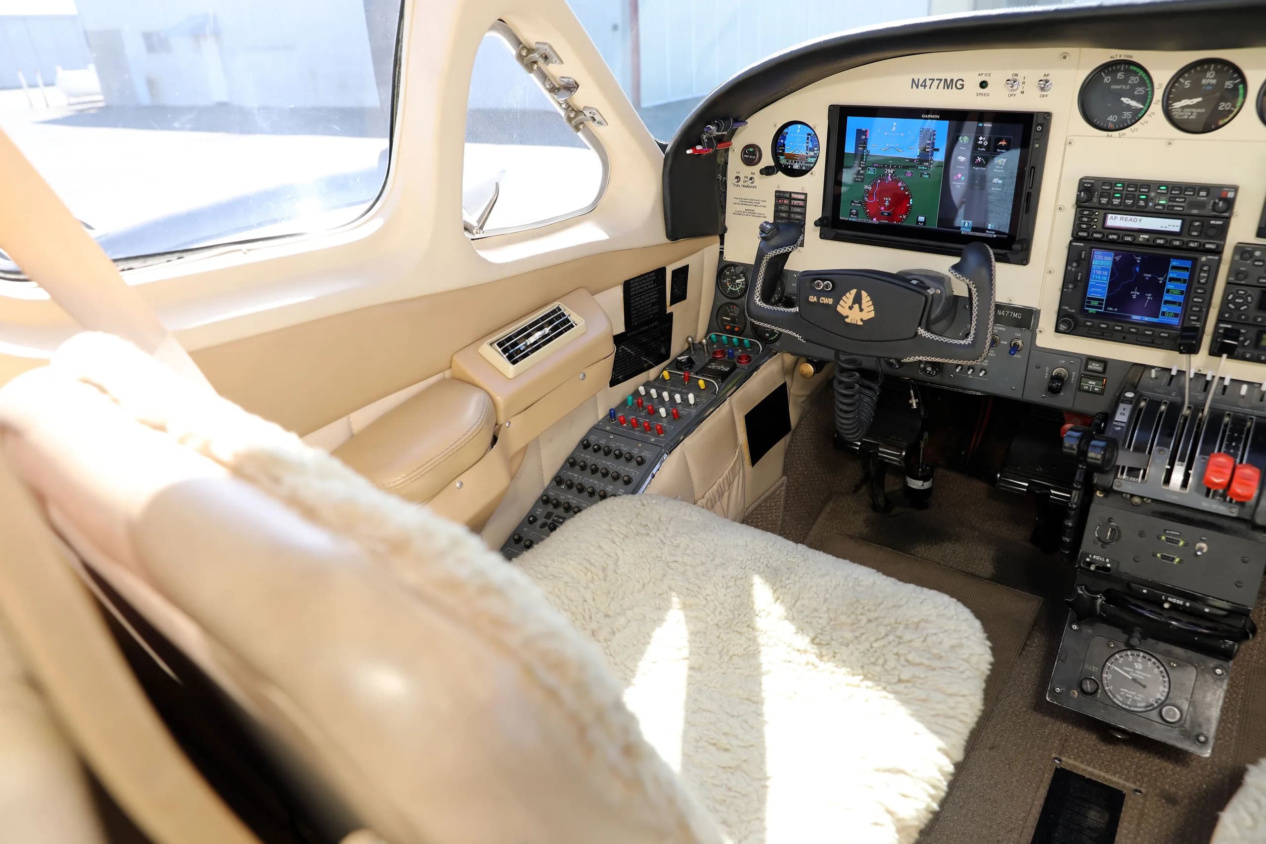 A view of the Cessna 414 Chancellor cockpit from the pilot's side, showing the instrument panel, controls, and a sheepskin seat cover.