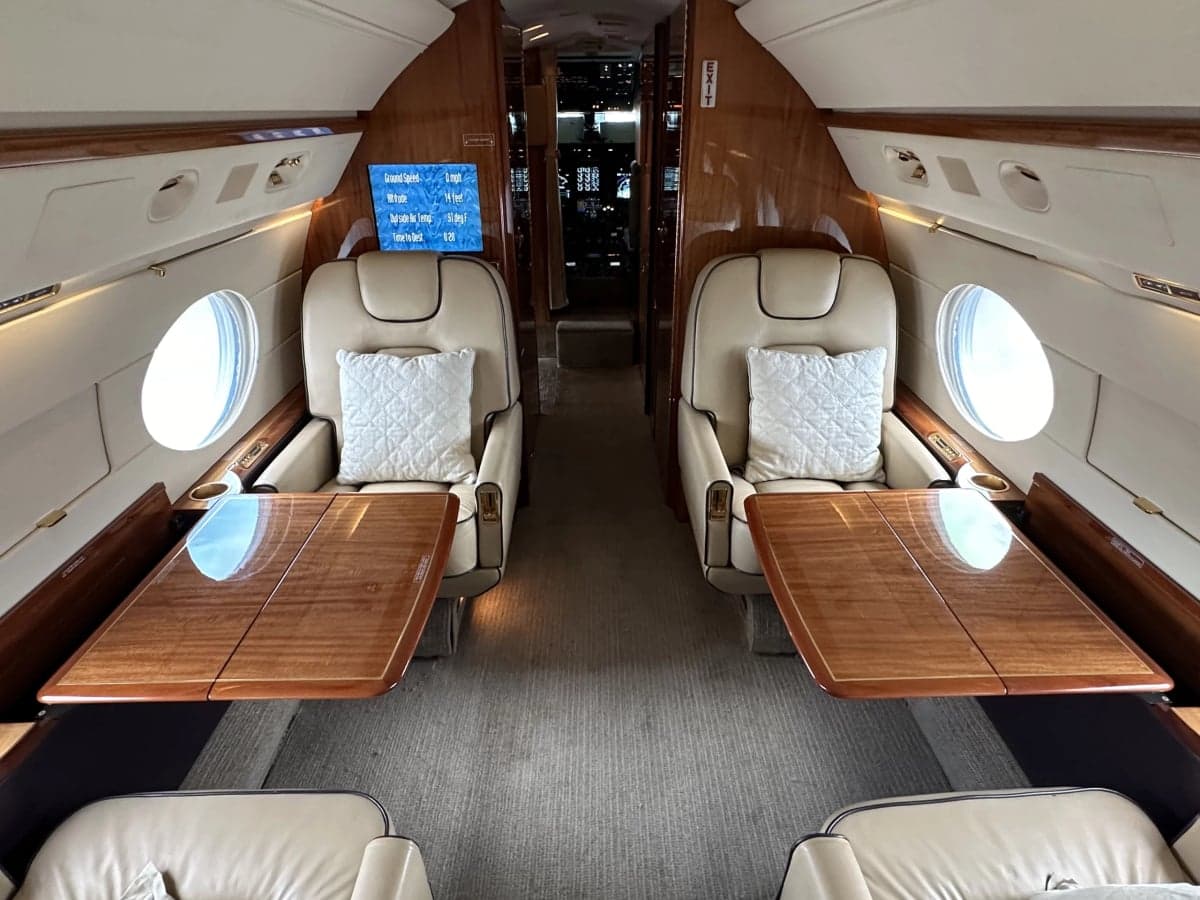 View of the aircraft interior with leather seats and wooden tables.