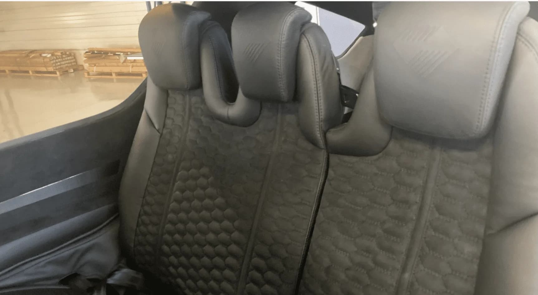Close-up view of the black leather aircraft interior seats with honeycomb pattern stitching.