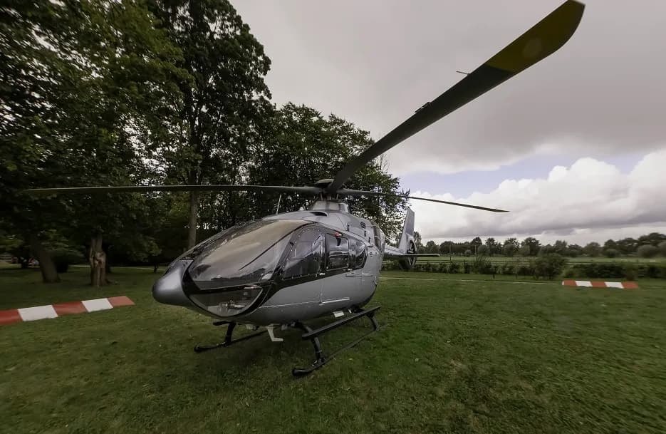 Front view of a silver and black helicopter parked on the grass.