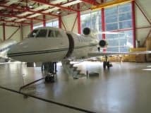 A white aircraft is parked inside a hangar.