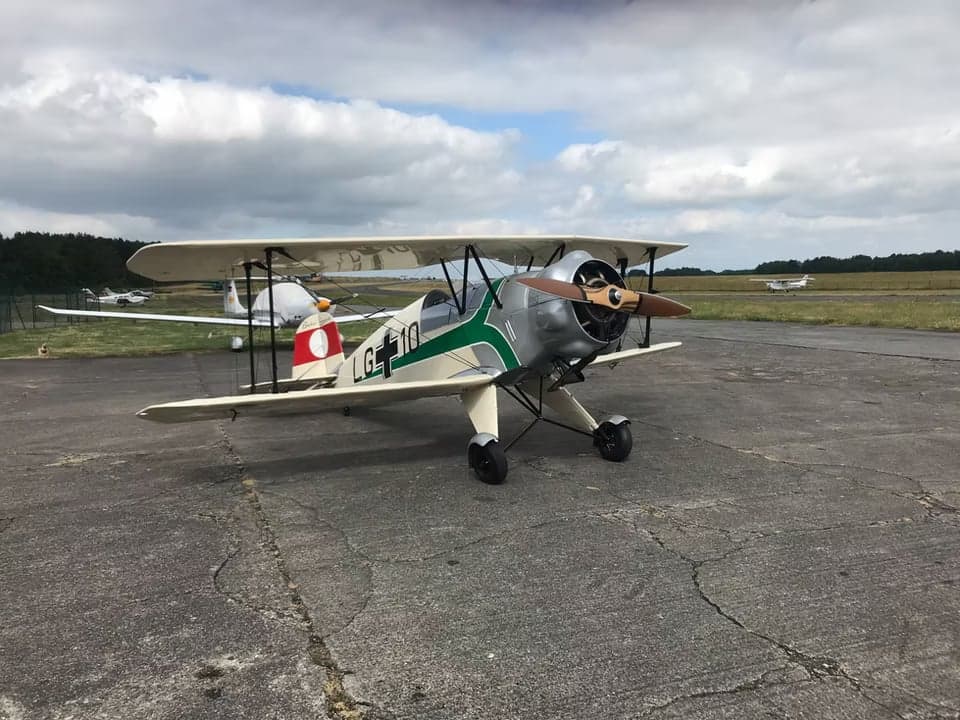 Side view of the biplane aircraft parked in front of a building.