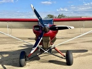 Front view of a red and white Carbon Cub aircraft on the ground.