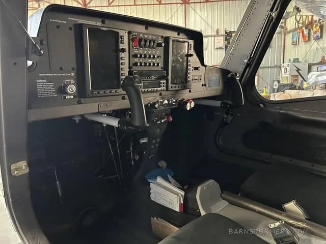A wide view of the dark gray cockpit of a light-sport aircraft, showing the instrument panel and controls.