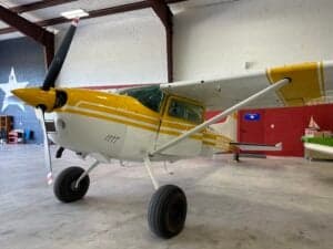 A Cessna 185 Skywagon, registration N185GS, is parked inside a hangar.