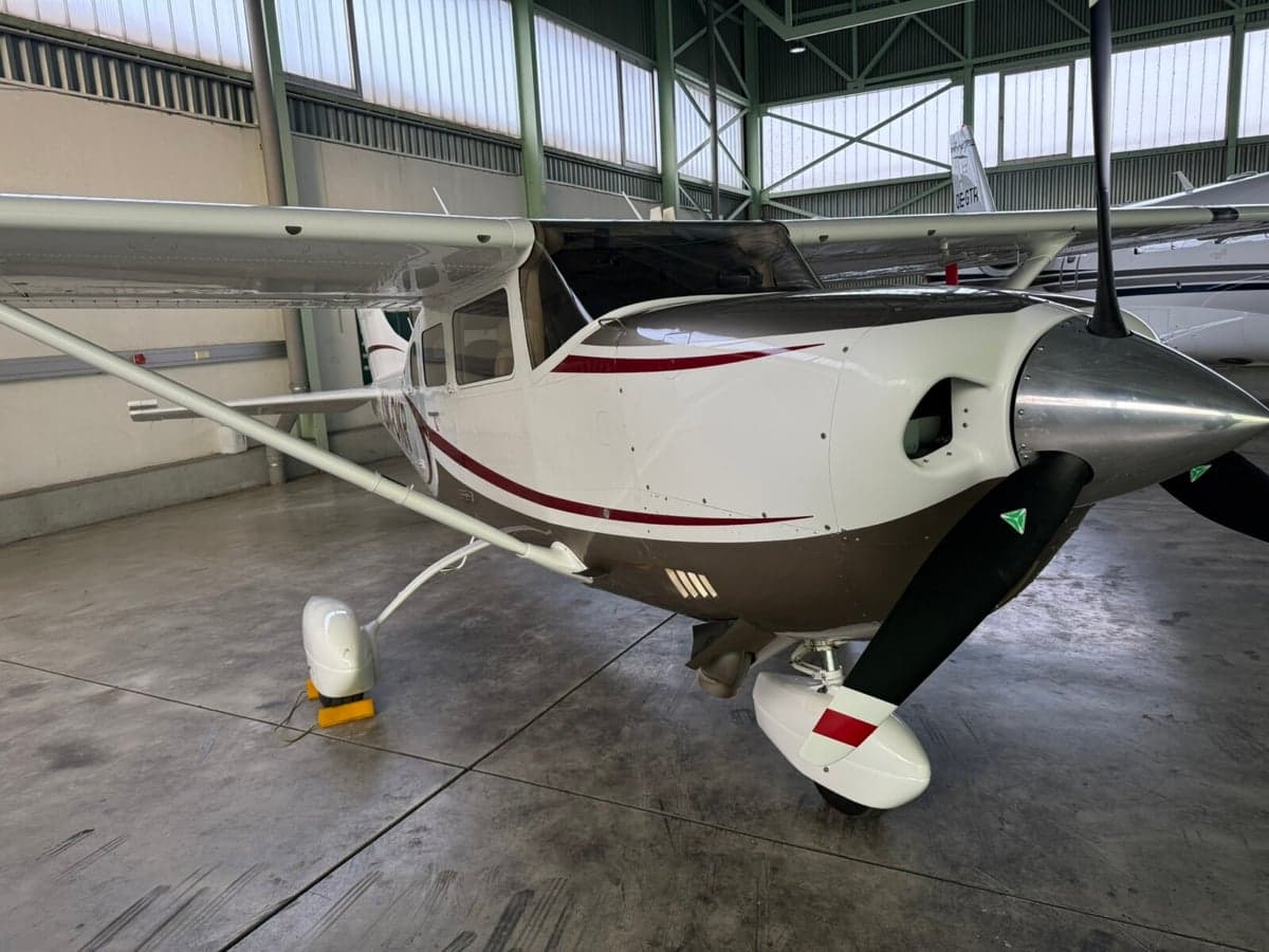 A Cessna aircraft is parked inside a hangar, showcasing its white and brown paint scheme.