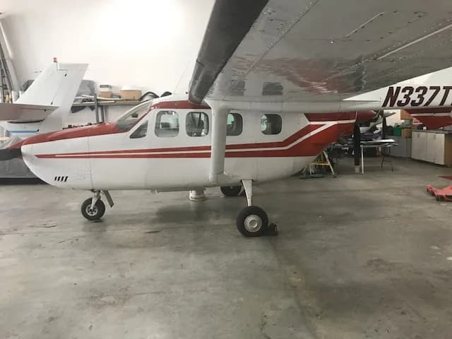 A side view of a white and red Cessna 337 Skymaster aircraft with registration N337TW in a hangar.