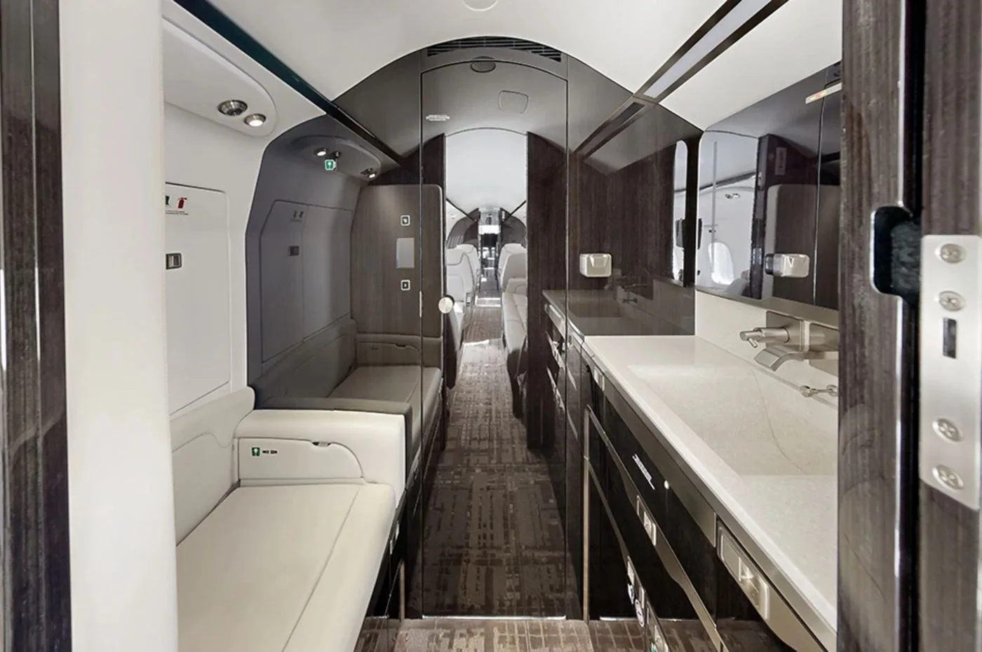 The private jet's lavatory with a modern sink, dark wood accents, and a white bench seat.
