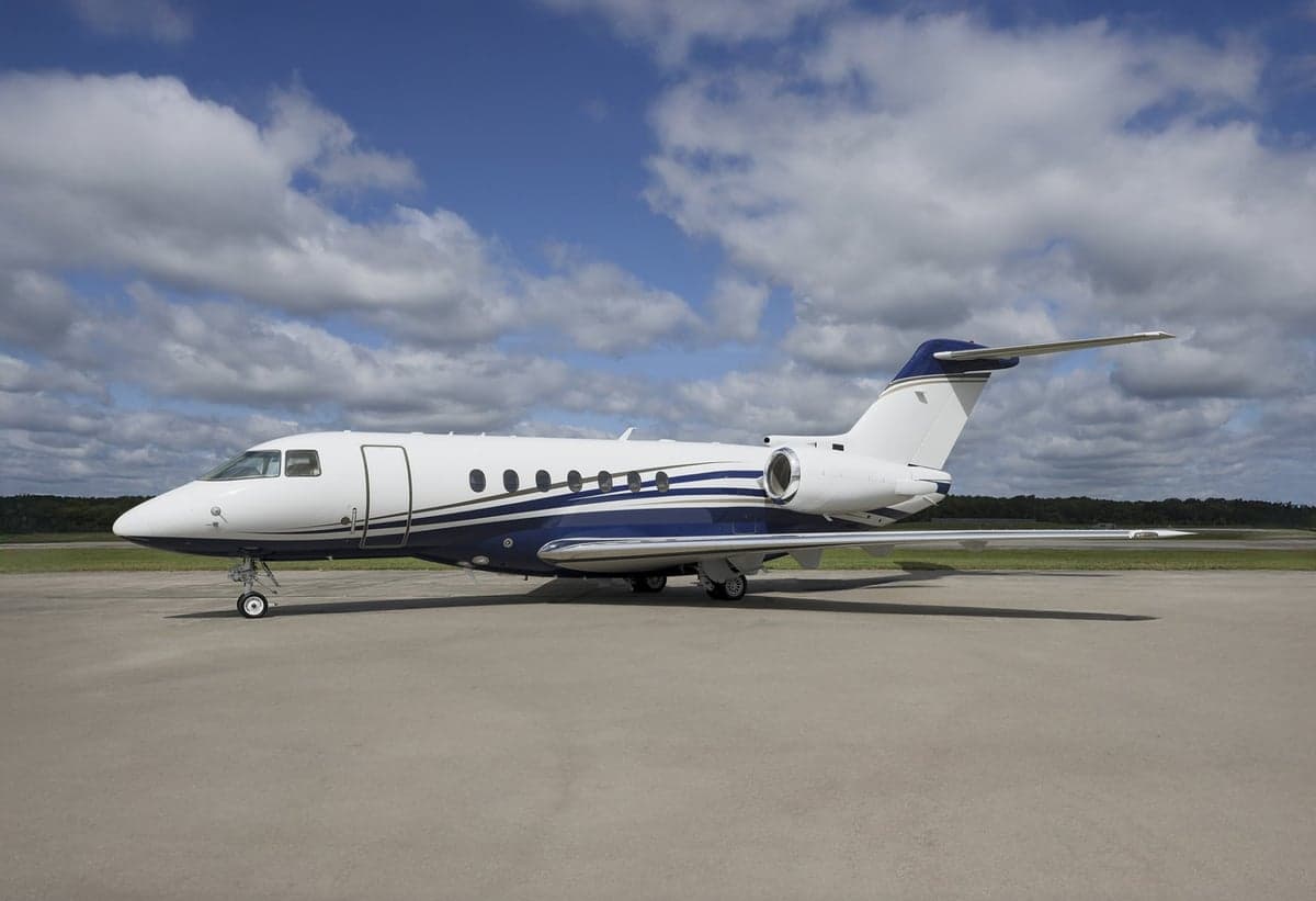 Side view of a white and blue jet aircraft on the tarmac.