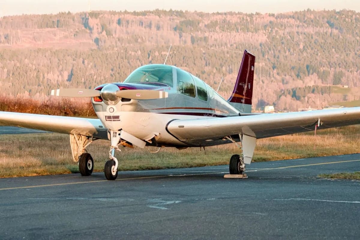 Beechcraft Bonanza N8918M parked on the runway with mountains in the background.