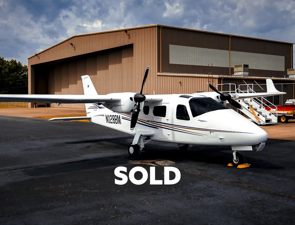 A Tecnam P2006T with registration N128BM is parked in front of a hangar, with a 'SOLD' overlay.