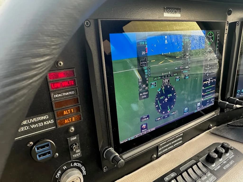A close-up of the Garmin primary flight display in the Cirrus SR22 cockpit, showing flight data and warnings.