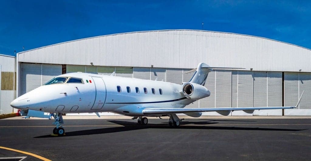 A Bombardier Challenger 300 parked on the tarmac in front of a hangar.