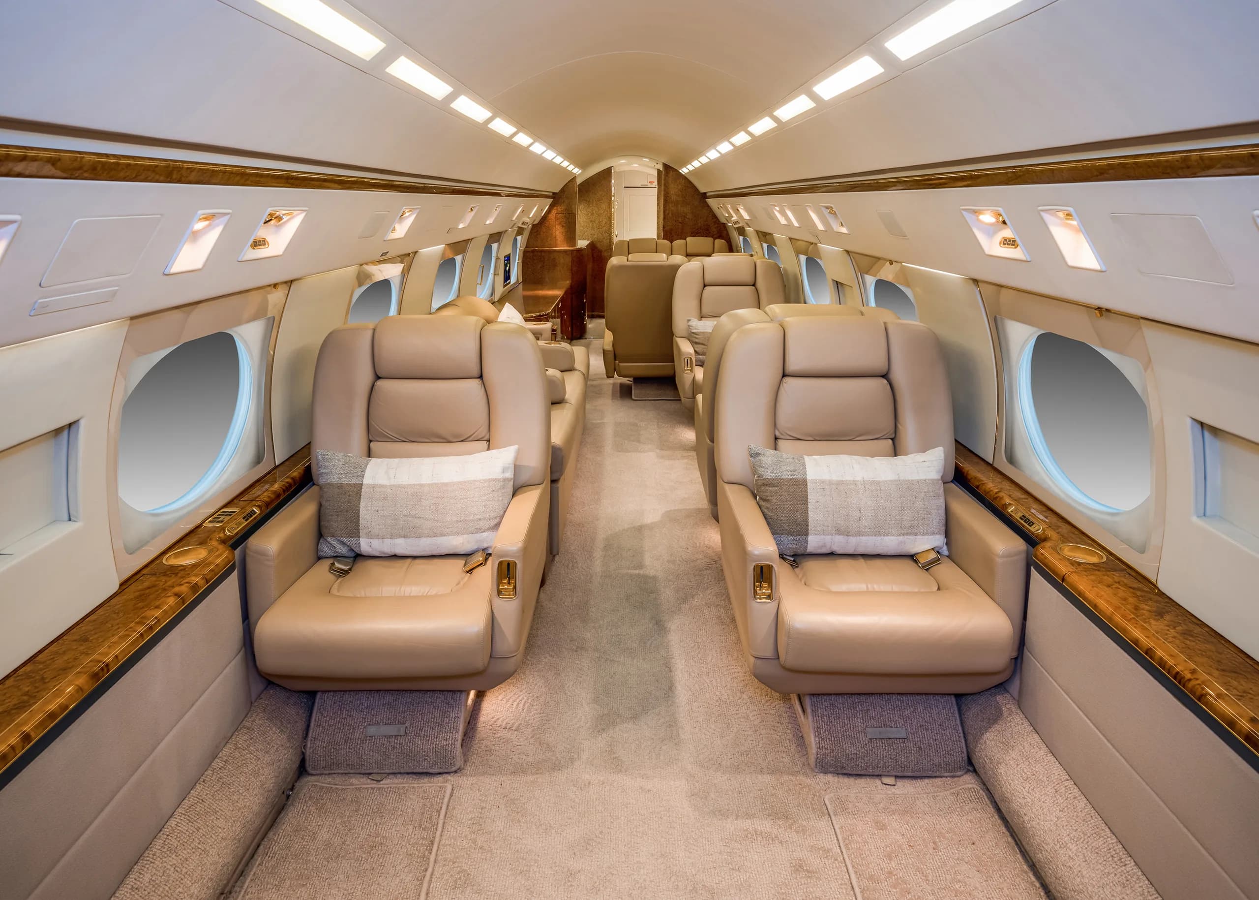 A symmetrical view of an aircraft cabin with beige leather seats and wood trim, looking towards the rear.