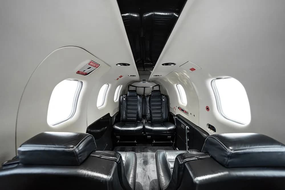 A wide-angle view of the TBM 930 cabin interior with black leather seats and a light-colored ceiling.