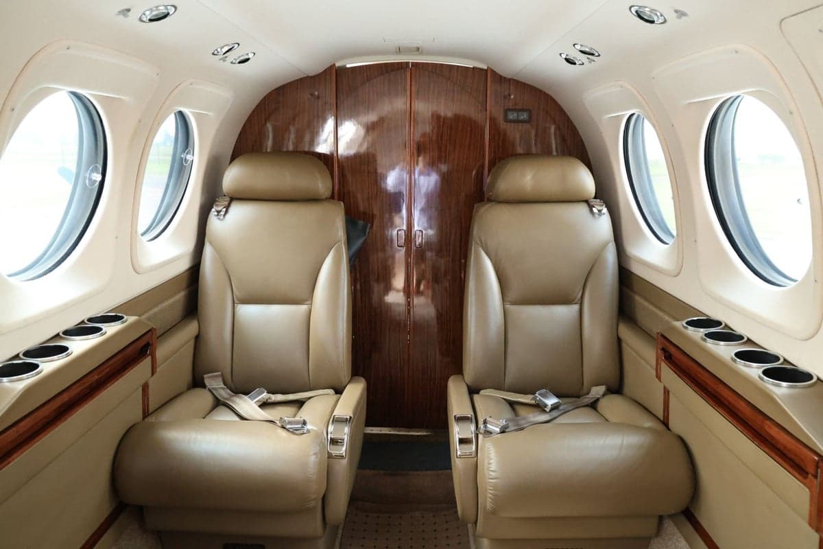 Interior view of an aircraft showing two leather seats with seatbelts.