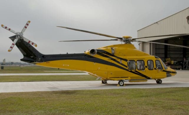 A yellow and black AgustaWestland AW139 helicopter is parked on the tarmac.