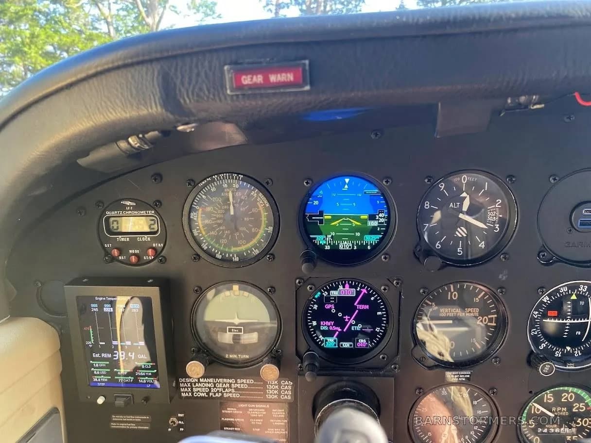 Close-up of an aircraft instrument panel featuring analog gauges and digital displays, including a "GEAR WARN" light.
