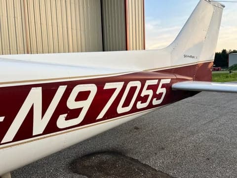 A close-up of the tail section of the Cessna Skyhawk N97055, showing its maroon and gold stripe paint scheme.