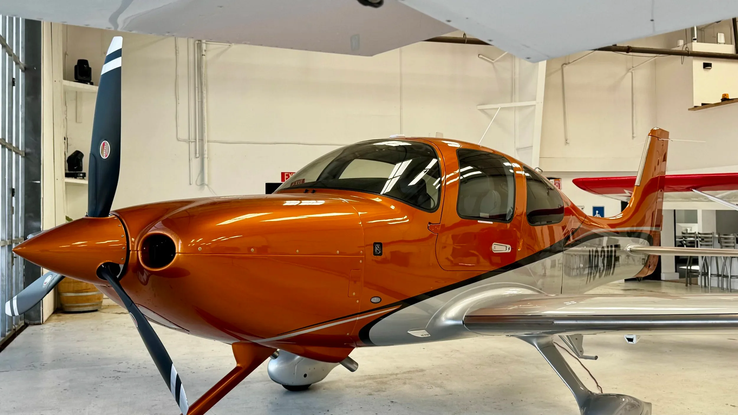 Close up of a Cirrus SR22 with an orange and silver paint scheme.