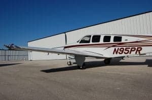 A Beechcraft Bonanza sits on the tarmac, showing the tail number.