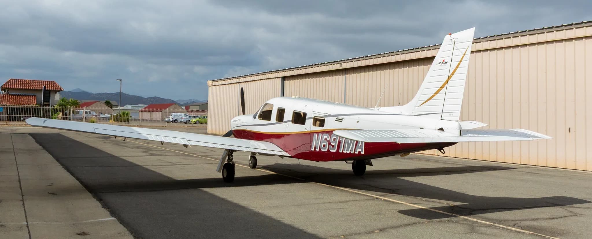 Rear three-quarter view of a white and maroon Piper Saratoga II TC aircraft, registration N691MA, parked on an asphalt ramp.