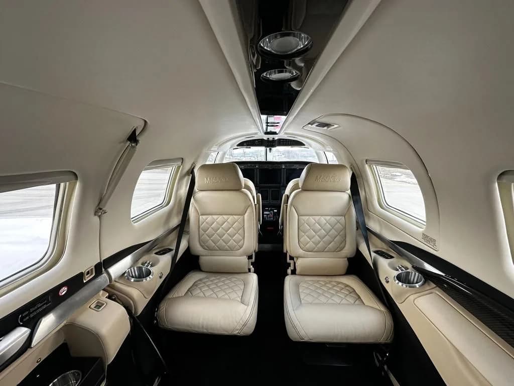 Interior view of a Piper M600 SLS cabin looking forward, with light-colored quilted leather seats.