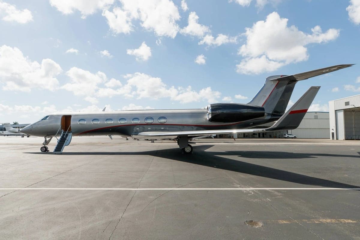 A Gulfstream G550 aircraft is parked on the tarmac with the boarding stairs down.