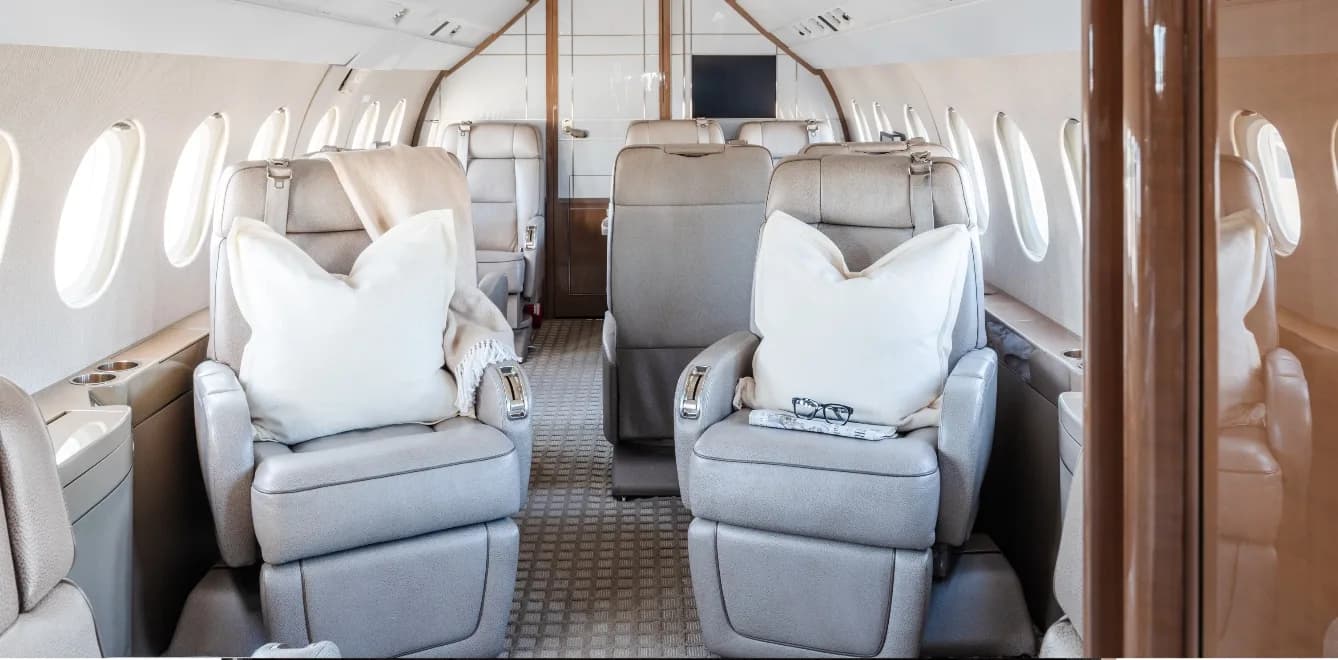 View of the aircraft's interior with light gray leather seats and pillows.