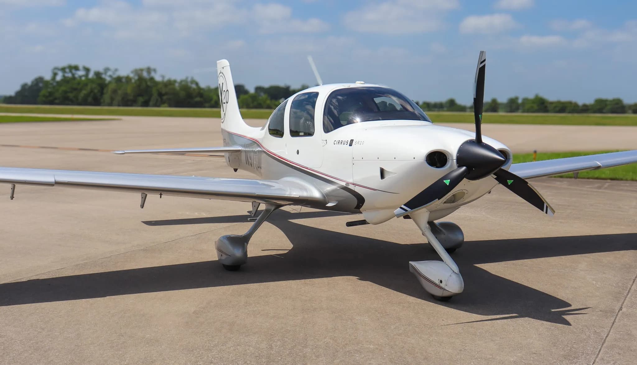 A white Cirrus SR20 X Edition aircraft with silver accents, parked on an airfield.