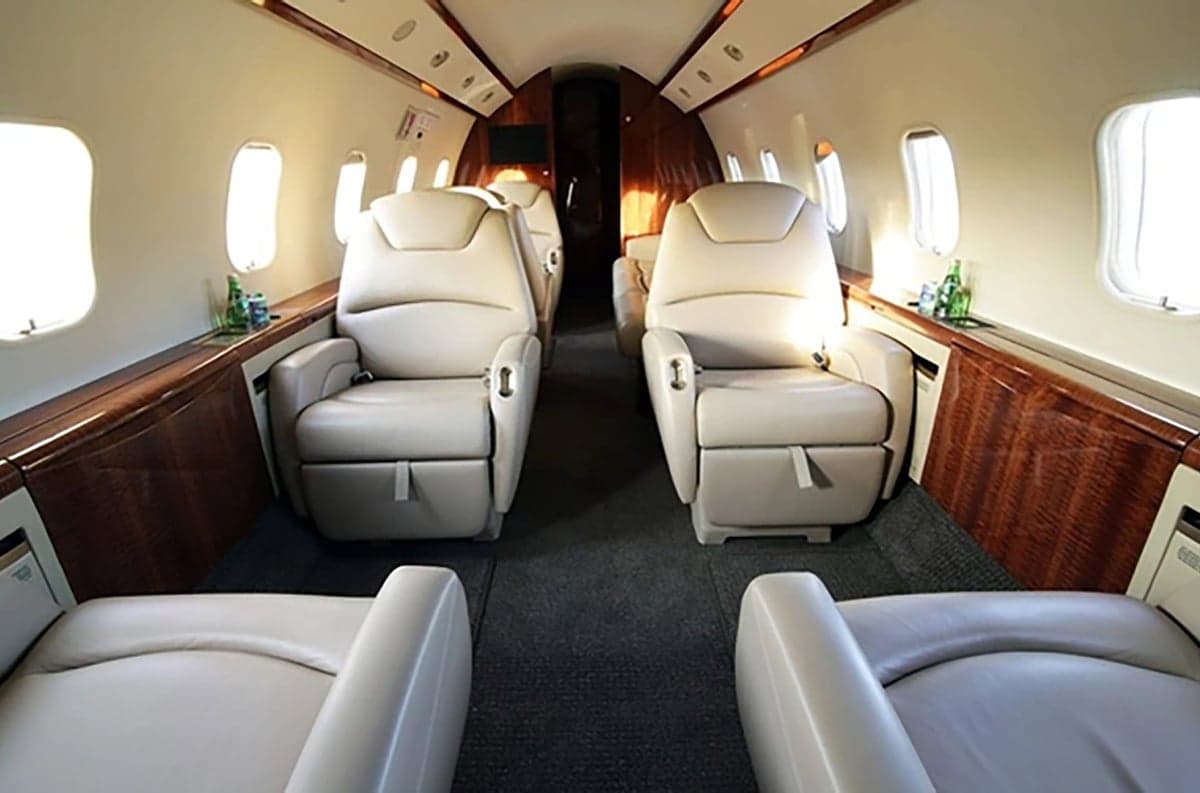 View of the aircraft interior with tan leather seats and wood trim.