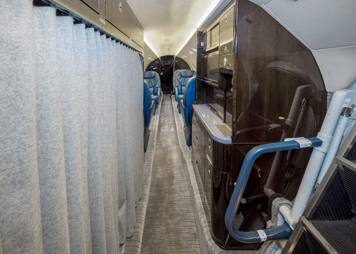 View of the aircraft interior featuring a curtain, blue leather seats, and a cabinet.