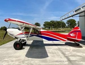A white and red aircraft is parked on the tarmac with a shark mouth design.