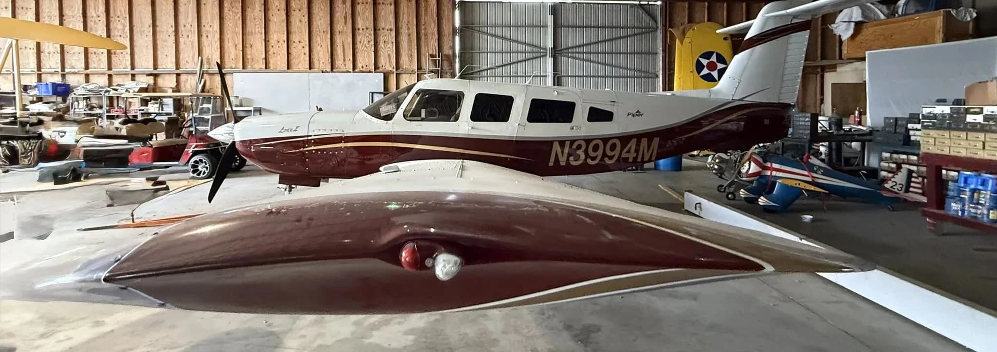 A close-up view of the Piper Lance II aircraft N3994M's wingtip and fuselage in a hangar.
