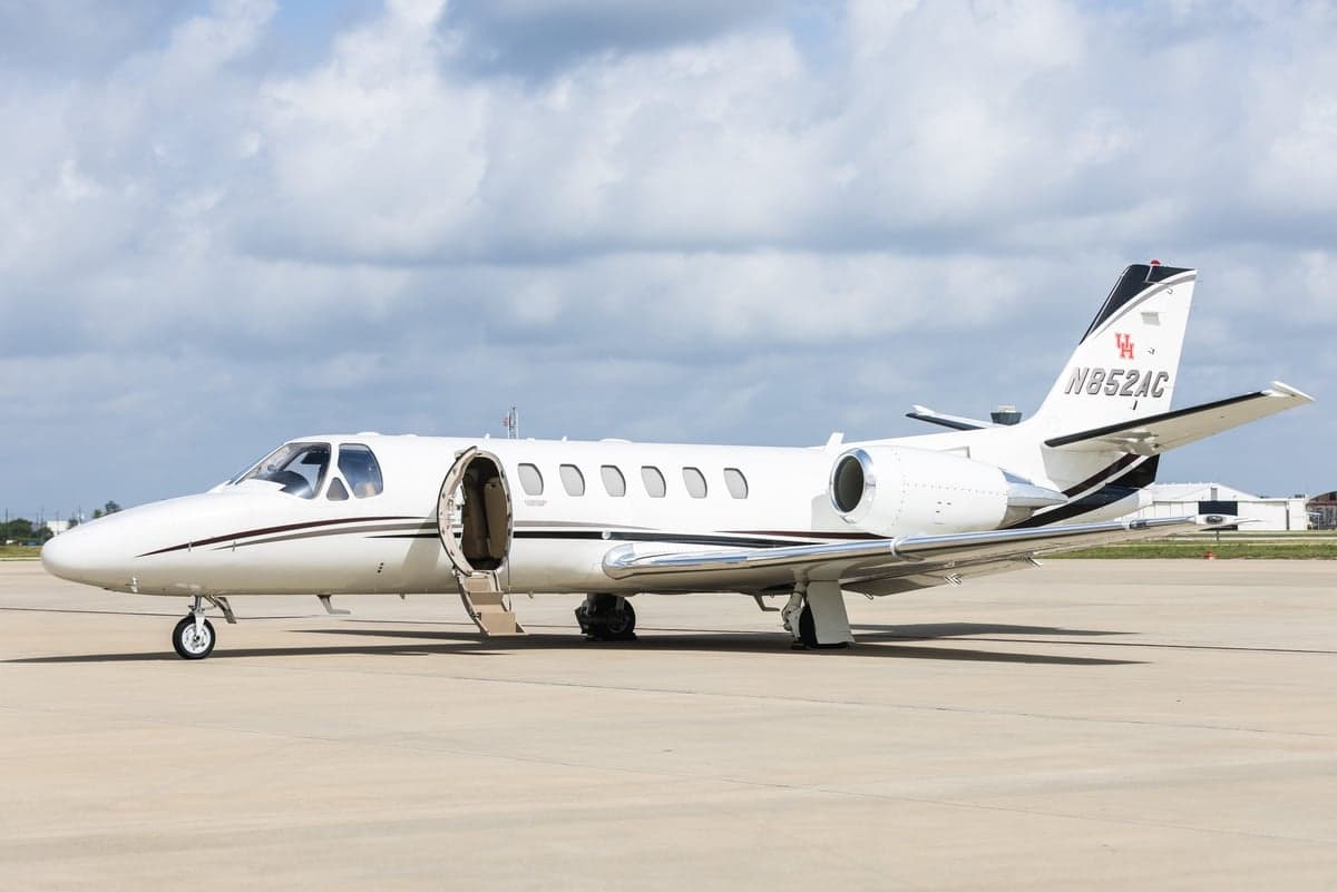 A white Cessna Citation CJ3 with the door open on the tarmac.